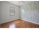 Cozy bedroom with window, wood-look floors, and designer accent wall with light colors at 1394 Palmetto Dunes St, Champions Gate, FL 33896
