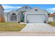 Charming single-Gathering home features a teal front door, well-maintained lawn, and an attached two-car garage at 142 Ethan Ave, Davenport, FL 33897