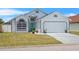 Charming single-Gathering home features a teal front door, well-maintained lawn, and an attached two-car garage at 142 Ethan Ave, Davenport, FL 33897
