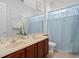 Bathroom features double vanity, decorative mirror, and tub with shower curtain at 15037 Cedar Branch Way, Orlando, FL 32824