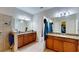 Bright bathroom with a dual sink vanity with granite countertop and a walk-in shower with light neutral tile at 1723 Brassie Ct, Kissimmee, FL 34746