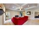 Bright living room featuring a tray ceiling, fan, neutral carpet, and a large red sectional sofa at 1723 Brassie Ct, Kissimmee, FL 34746