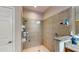 Close-up of the walk-in shower with neutral toned tile and a glass shelving unit for toiletries at 1723 Brassie Ct, Kissimmee, FL 34746