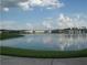 View of pond surrounded by landscaped green spaces and community buildings at 3001 Greystone Loop # 106, Kissimmee, FL 34741