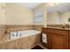 This bathroom boasts a tiled soaking tub and a vanity with granite countertop and neutral decor at 3391 Cortland Dr, Davenport, FL 33837