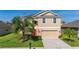 Charming two-story home with a well-manicured lawn, vibrant landscaping, and a welcoming red front door at 3391 Cortland Dr, Davenport, FL 33837