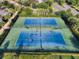 Aerial view of the community tennis courts surrounded by mature trees and lush landscaping at 341 Lasso Dr, Kissimmee, FL 34747