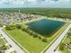 Aerial view of a lush neighborhood with a serene pond surrounded by greenery and homes at 4726 Ashurst St, Kissimmee, FL 34758
