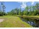 Picturesque waterfront featuring a calm canal bordered by vibrant green grasses and lush trees at 4730 Cypress Creek Ranch Rd, St Cloud, FL 34771