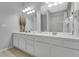 Bathroom featuring a dual sink vanity with large mirrors, modern lighting, and wood look flooring at 5038 Tideview Cir # 21, Orlando, FL 32819