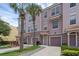 Three-story townhome featuring individual garages, private entrances and lush tropical landscaping with palm trees at 5038 Tideview Cir # 21, Orlando, FL 32819
