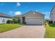 Attractive one-story home with verdant grass, a brick driveway, and attached garage under a bright blue sky at 5133 Chickadee St, St Cloud, FL 34771
