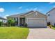Charming single-story home with a manicured lawn, paver driveway, and a two-car garage under a sunny blue sky at 5133 Chickadee St, St Cloud, FL 34771