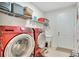 Laundry room featuring red Samsung washer and dryer with a utility sink and storage at 5133 Chickadee St, St Cloud, FL 34771
