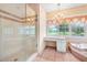 Bathroom featuring glass shower, tub, chandelier, and a vanity under a window at 5150 Gentry Oaks Pl, St Cloud, FL 34772