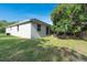 Backyard with partial view of the house and a large tree providing shade over the lawn at 6479 Apple St, St Cloud, FL 34771