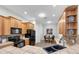 Bright kitchen with wooden cabinets, tile countertops, black appliances and a view of dining area at 6479 Apple St, St Cloud, FL 34771