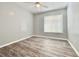 Bright bedroom featuring wood-look floors, neutral paint, ceiling fan, and a large window at 713 Wood Ln, Kissimmee, FL 34759
