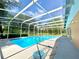 Screened-in pool with pool hose sitting next to it, surrounded by greenery and trees at 713 Wood Ln, Kissimmee, FL 34759