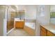 This bathroom features a garden tub, glass shower, and wood cabinets at 7740 Linkside Loop, Reunion, FL 34747