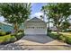 Two-car garage with matching trim and doors, trimmed with bushes and trees, sits next to a light blue house at 7740 Linkside Loop, Reunion, FL 34747