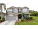 Charming two-story home featuring a manicured lawn, mature landscaping, and a two car garage at 805 Suffolk Pl, Davenport, FL 33896