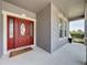 Inviting front entry with a decorative red door, a welcome mat, sidelights, and covered porch for added curb appeal at 805 Suffolk Pl, Davenport, FL 33896