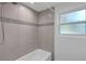 Shower with gray tiling, mosaic border, and a window for natural light at 807 E Airport Blvd, Sanford, FL 32773
