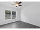 This bedroom features wood-look floors, a ceiling fan, and natural light from a window overlooking the backyard at 807 E Airport Blvd, Sanford, FL 32773
