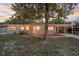 Single-story home features a cozy porch, warm lighting, and an inviting front yard shaded by mature trees at 807 E Airport Blvd, Sanford, FL 32773