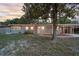 Single-story home features a cozy porch, warm lighting, and an inviting front yard shaded by mature trees at 807 E Airport Blvd, Sanford, FL 32773