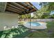 Backyard with a covered patio and round in-ground pool surrounded by artificial turf and a privacy fence at 807 E Airport Blvd, Sanford, FL 32773
