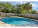 This backyard features a sparkling pool, surrounded by a wooden fence and green trees at 807 E Airport Blvd, Sanford, FL 32773