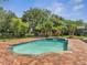 Inviting pool area featuring a brick patio and lush tropical landscaping, perfect for relaxation and outdoor enjoyment at 13130 Meergate Cir, Orlando, FL 32837