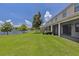 Backyard view featuring a meticulously maintained lawn, lake view, and screened in porch at 1628 Portofino Meadows Blvd, Orlando, FL 32824