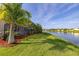 Serene backyard with lush lawn leading to a tranquil lake, bordered by mature palm trees at 1760 Boat Launch Rd, Kissimmee, FL 34746