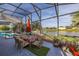 Screened in patio with colorful dining set, overlooking a peaceful pond and manicured lawn at 1760 Boat Launch Rd, Kissimmee, FL 34746