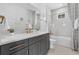 Stylish bathroom featuring gray vanity with gold hardware and white tiled shower and gold fixtures at 1801 Coastal Ct, Celebration, FL 34747