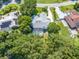 Aerial view of a home with a screen enclosed pool and spa surrounded by mature trees and lush landscaping at 2376 Nightingale Ln, Kissimmee, FL 34746