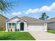 Charming single-story home featuring a two-car garage, well-kept lawn, and blue shutters at 2416 White Poppy Dr, Kissimmee, FL 34747