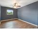 Bedroom with wood-look flooring, ceiling fan, and window with a view of trees at 31 Lake Link Se Cir, Winter Haven, FL 33884