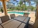 Outdoor dining on patio, with a view of the screened pool and surrounding lush greenery at 315 Wildflower Rd, Davenport, FL 33837