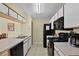 Efficient kitchen featuring black appliances, white cabinets, tile floor and a bright overhead light at 3151 Britannia Blvd # C, Kissimmee, FL 34747