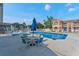 Community swimming pool with lounge seating, tables with umbrellas, and nearby apartment buildings at 3151 Britannia Blvd # C, Kissimmee, FL 34747