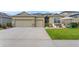 Inviting home exterior with a well-manicured lawn, stone accents, a two-car garage, and a charming front patio at 3698 Cortland Dr, Davenport, FL 33837
