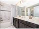 Bright bathroom featuring a double sink vanity, tub with shower, and marble tile surround at 4903 Windermere Ave, Kissimmee, FL 34746
