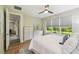 Bright main bedroom featuring a king-size bed, ceiling fan, natural light, and views of the lush greenery outside at 582 San Joaquin Rd, Poinciana, FL 34759