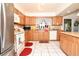 Kitchen showcases oak cabinets, tiled floors, a stainless steel refrigerator, and an island counter with bar stools at 860 Oak Shore Dr, St Cloud, FL 34771