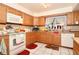 Kitchen boasts oak cabinets, tile backsplash, and white appliances with tiled floors and lots of natural light at 860 Oak Shore Dr, St Cloud, FL 34771