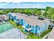 Aerial view of blue condo buildings with balconies, a tennis court, and lush green landscaping at 8716 Rain Forest Pl # D, Kissimmee, FL 34747
